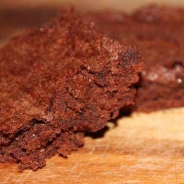 Two pieces of cocoa brownies on a wooden surface.