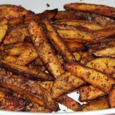 Close-up of spiced, roasted french fries in a white bowl.