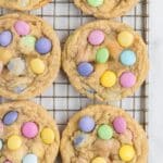 Cookies with colorful candy-coated chocolates on a cooling rack.