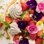 A naked cake topped with whipped cream, strawberries, raspberries, and colorful flowers. Text at the bottom reads, "Naked Cake with Flowers & Fruit.