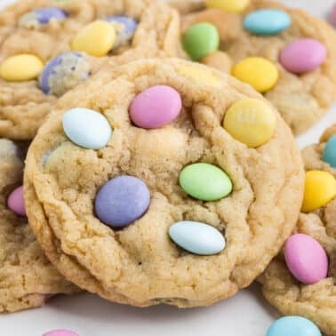 Cookies topped with colorful candy-coated chocolate pieces, scattered on a white surface.