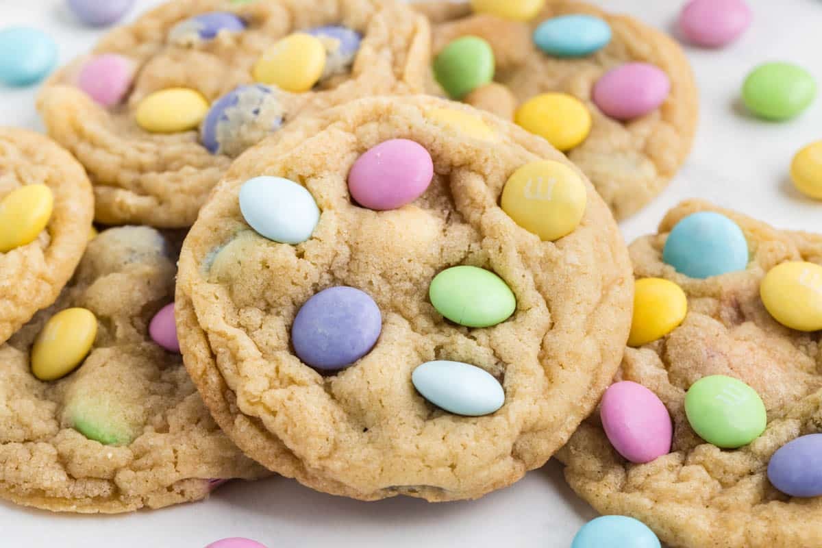 Cookies topped with colorful candy-coated chocolate pieces, scattered on a white surface.