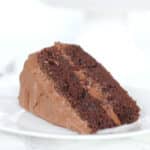 A slice of Hershey's chocolate cake with chocolate frosting on a white plate.