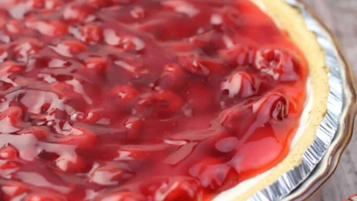 Close-up of a cherry pie with glossy red cherry filling in a metal pie tin, perfect for fans of juicy cherry desserts.