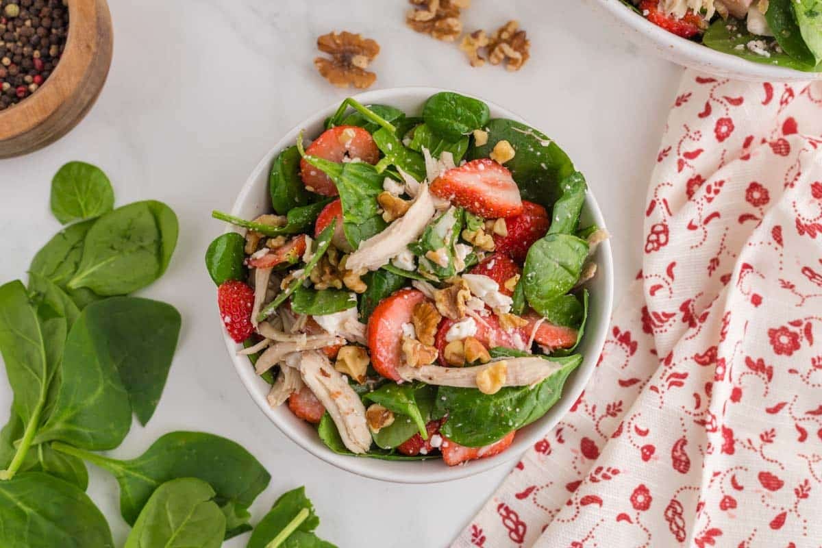 This spinach salad with strawberries, chicken, feta, and walnuts topped with a maple balsamic 