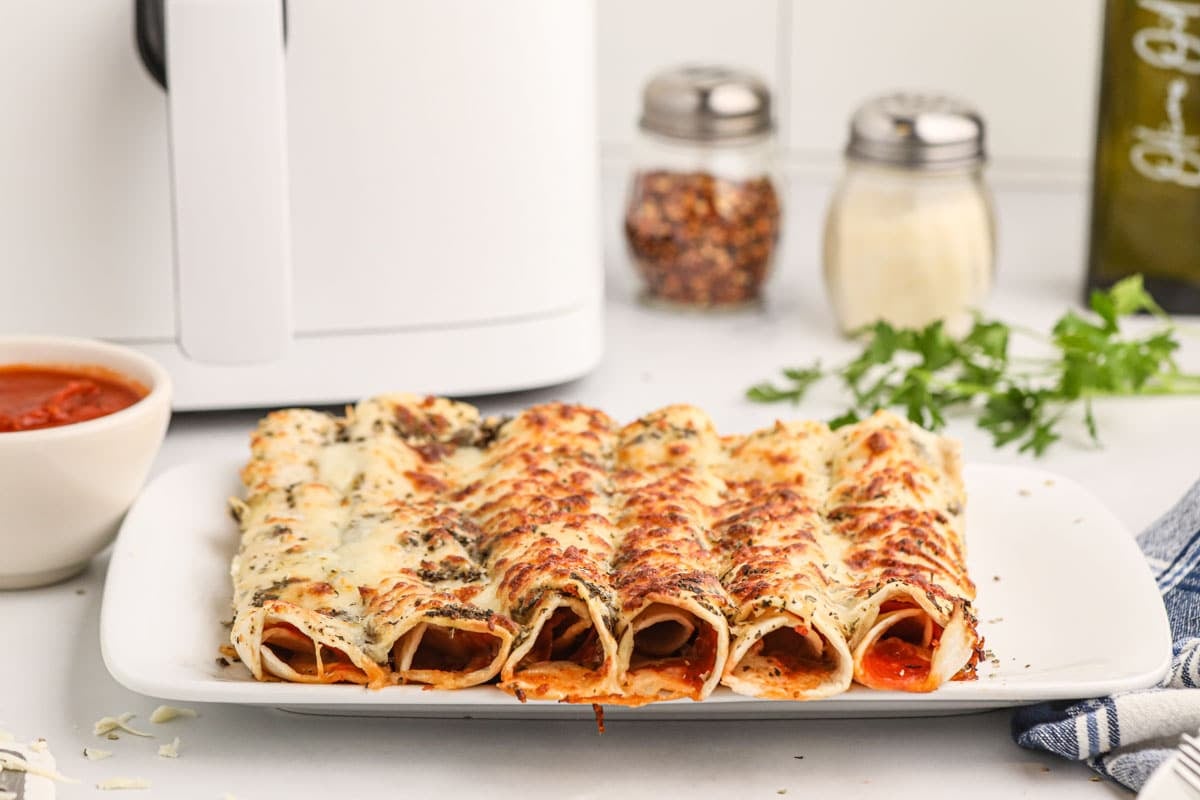 Cheesy air fryer pizza roll-ups with sauce, pepperoni, and garlic butter wrapped in crispy tortillas