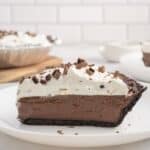 A slice of chocolate cream pie with whipped topping and chocolate shavings, served on a white plate.