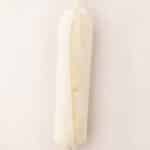 A roll of compound butter wrapped in parchment paper with twisted ends, placed on a light surface.