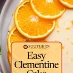 A clementine cake topped with thinly sliced clementines on a white plate, with text overlay reading "Easy Clementine Cake Get The Step-By-Step Recipe.