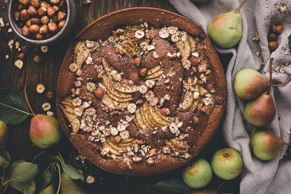 A moist chocolate hazelnut cake topped with juicy pears and crunchy hazelnuts, dusted with cocoa