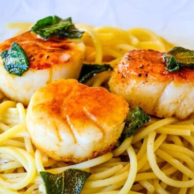 Three seared scallops served on a bed of spaghetti with fresh herbs make this dish a standout among quick seafood recipes, perfect for warm night dinners.