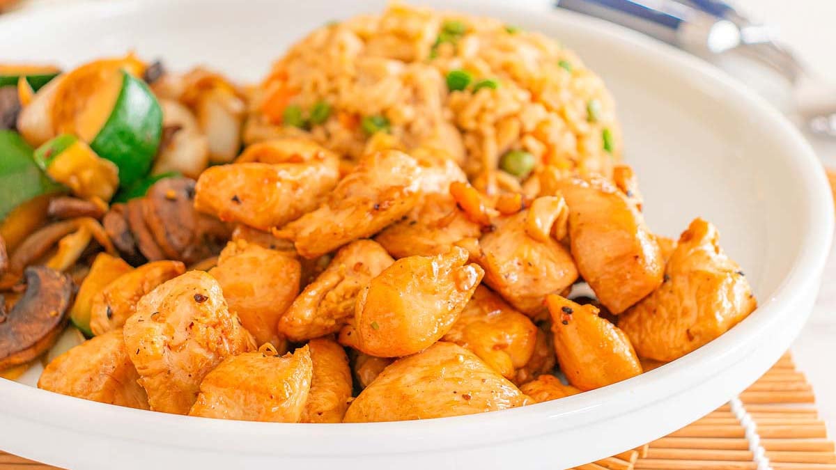 A plate with grilled chicken pieces, sautéed vegetables, and a serving of fried rice with peas and carrots—perfect for those seeking easy dinner ideas or delicious chicken recipes.