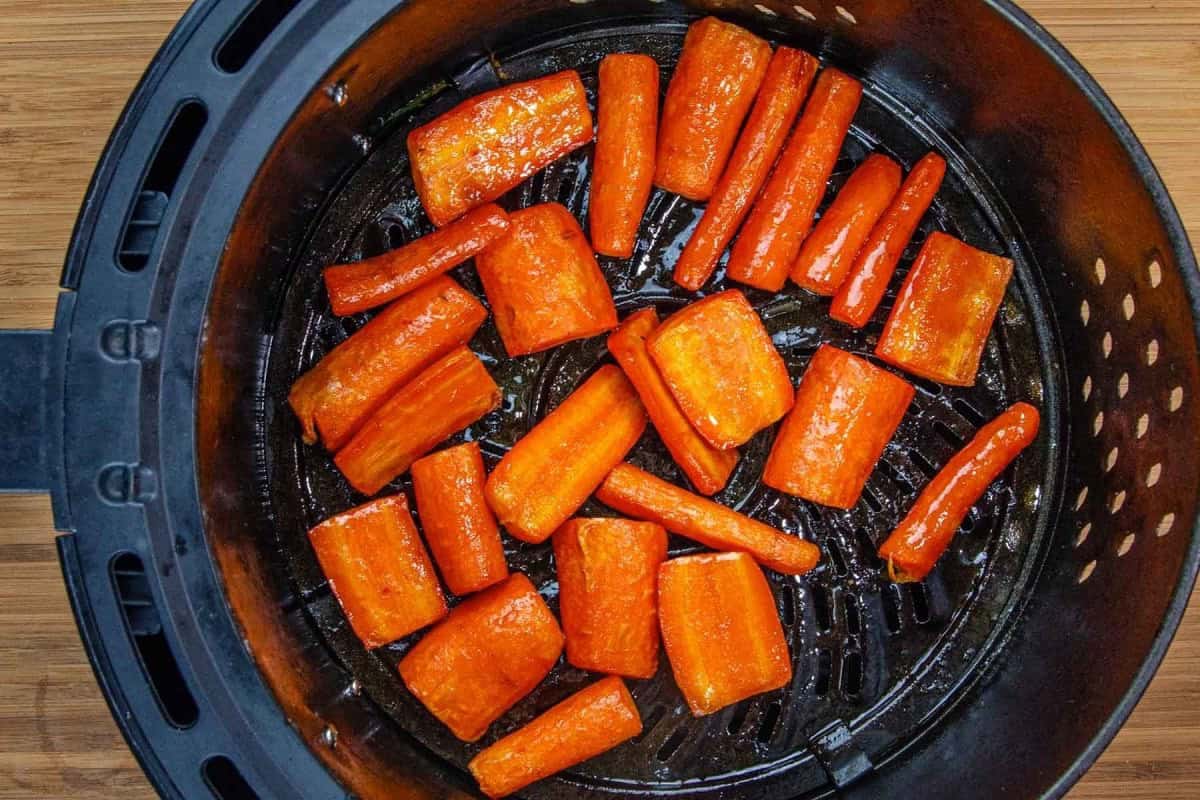 Chopped carrots coated in seasoning are arranged inside an air fryer basket, ready for cooking—a perfect addition to your side dishes or even as a vibrant main event.