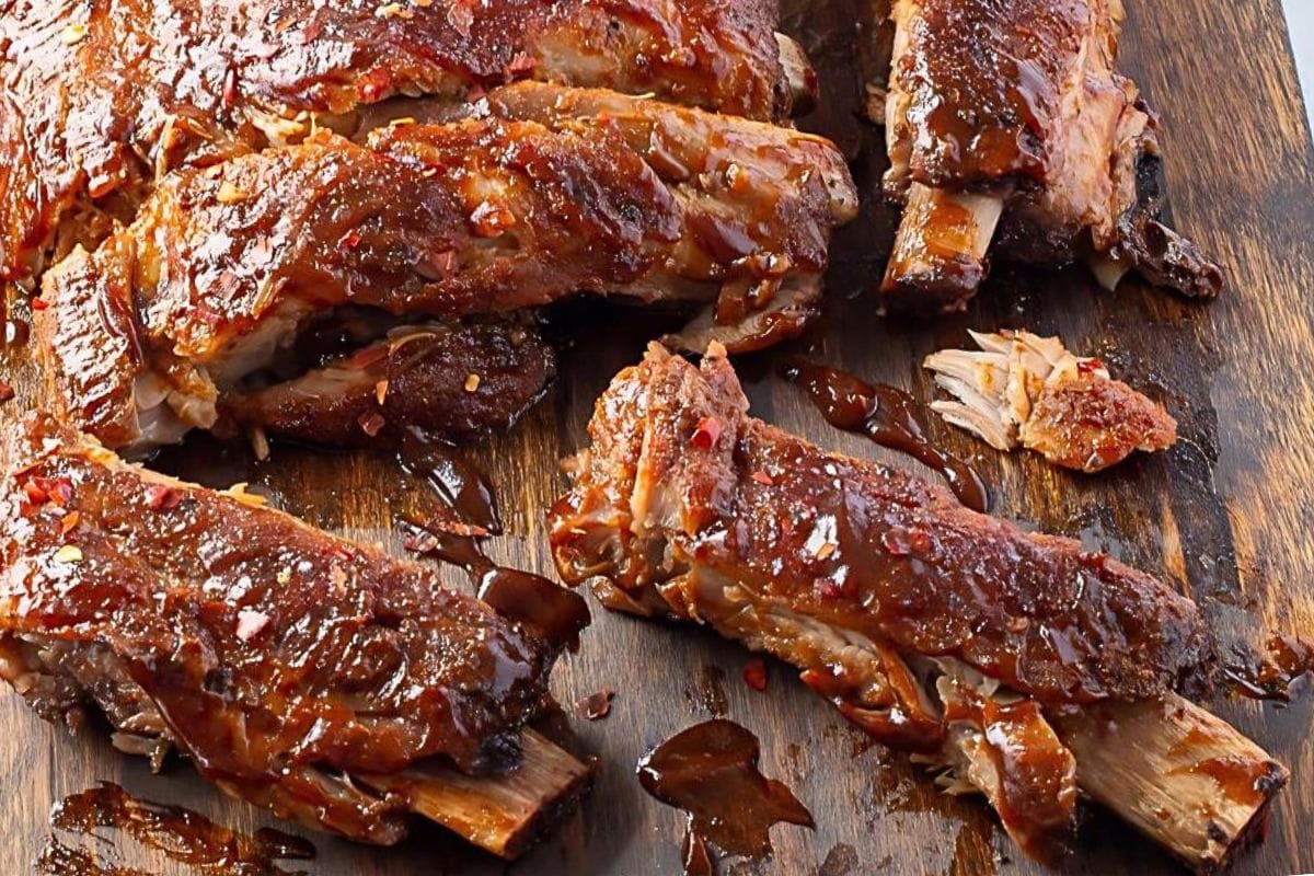 Barbecued ribs covered in sauce, sliced and arranged on a wooden cutting board—perfect for pork dinners and new dinner ideas.