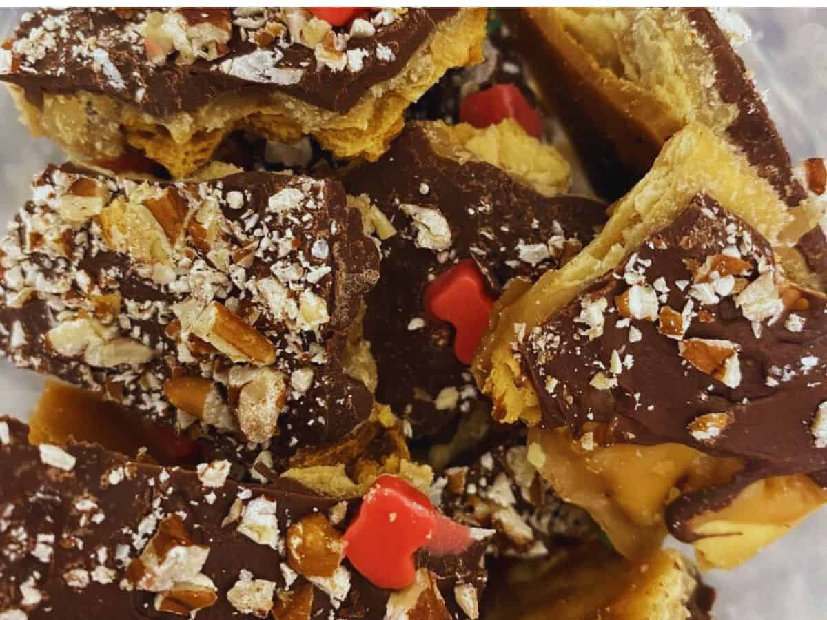 Close-up of chocolate toffee bark topped with chopped nuts and red candy pieces, stacked in a pile—perfect for holiday cooking and festive recipes.