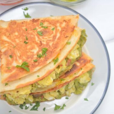 Two folded quesadillas filled with egg and green vegetables, garnished with chopped parsley, served on a white plate—perfect for easy school breakfasts and quick kids breakfast recipes.
