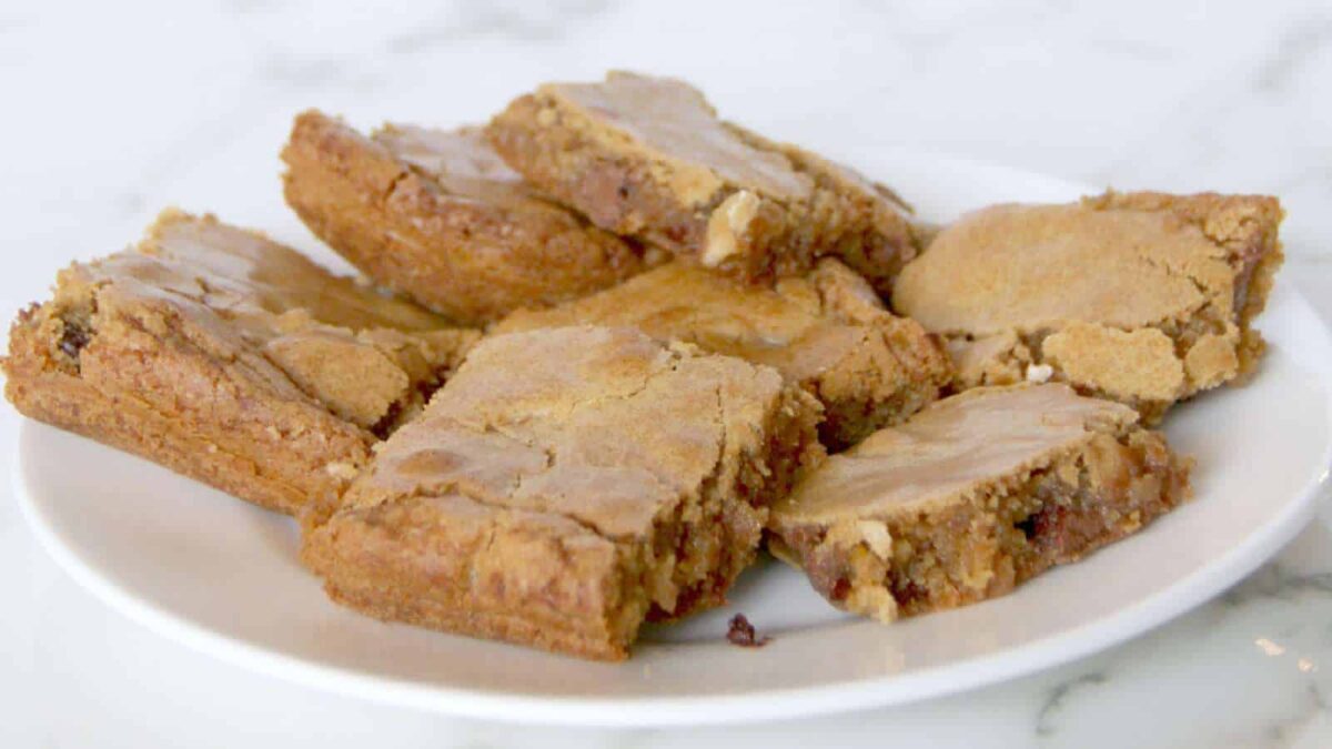 A white plate with several rectangular pieces of blondies, showing a golden brown crust and visible chunks of nuts—perfect for trying new blondie recipes or adding to your favorite dessert recipes collection.