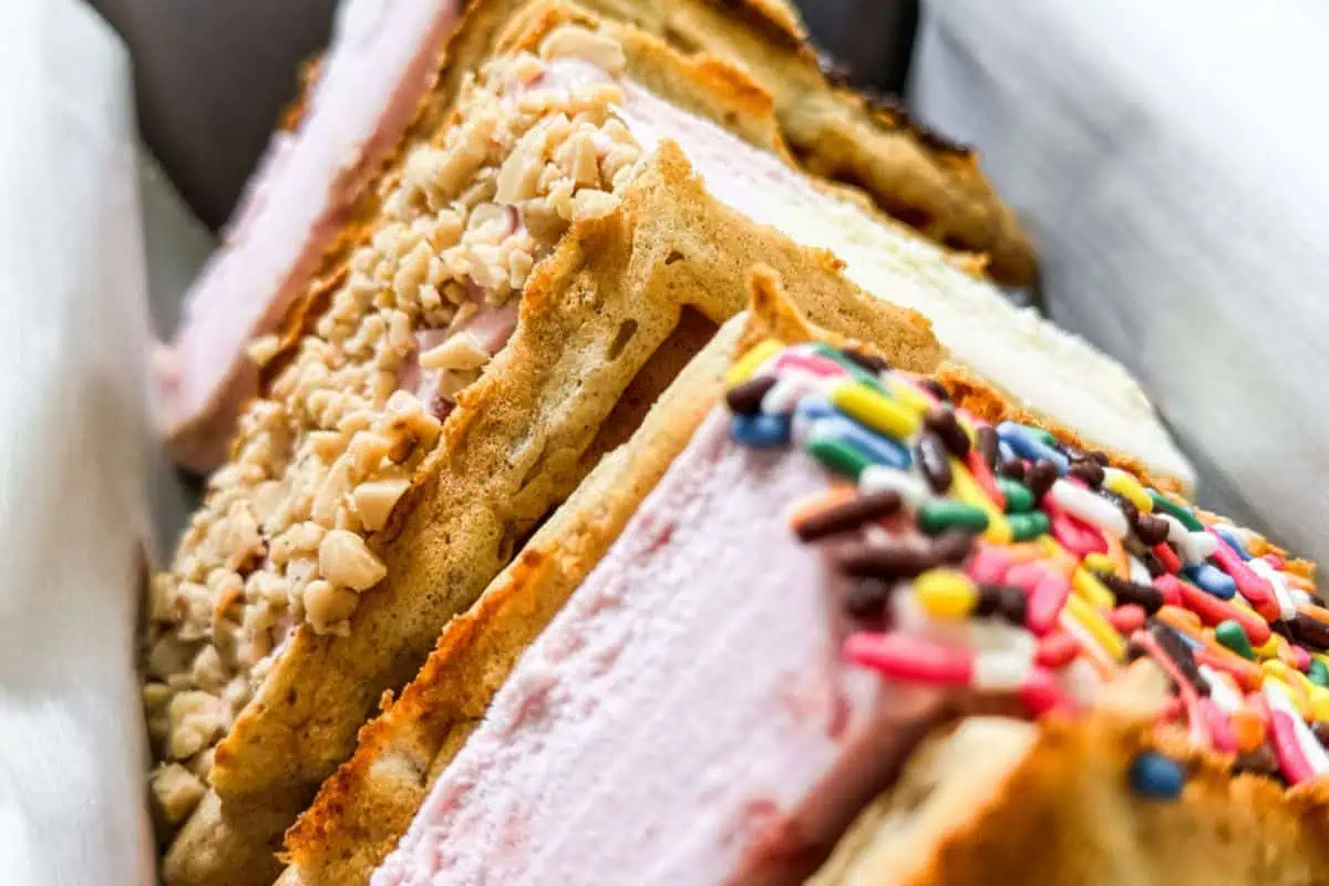 Close-up of delicious ice cream sandwiches with waffle cookies, topped with chopped nuts and colorful sprinkles—a delightful treat for ice cream desserts lovers.