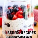 A glass filled with layers of chia pudding, fresh blueberries, and chopped strawberries sits on a wooden surface. Text reads "11 Berry Recipes Bursting With Flavor.