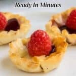 Three phyllo pastry cups filled with jam and topped with fresh raspberries on a white plate. Text reads: “14 Easy Appetizers Ready In Minutes.”.