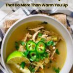 A bowl of chicken soup, one of the best healthy soups, garnished with sliced jalapeños, cilantro, and a lime wedge, sits on a cloth napkin with a spoon beside it.