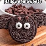Close-up of a cookie made to look like a bat with candy eyes and chocolate chip fangs, with text reading "16 Monster Themed Halloween Sweets.