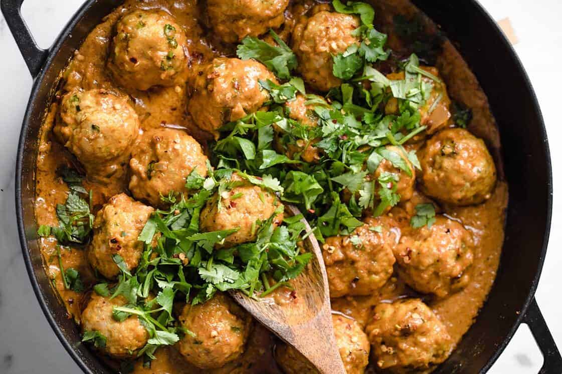 Meatballs in a brown sauce topped with chopped fresh cilantro, served in a black skillet with a wooden spoon—perfect for easy weeknight meals or anyone craving delicious turkey dinners.