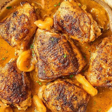 Golden-brown chicken thighs in a skillet with a thick, orange-brown sauce and apricots, garnished with herbs—perfect for one-pot chicken dinners and anyone seeking easy chicken dinners.