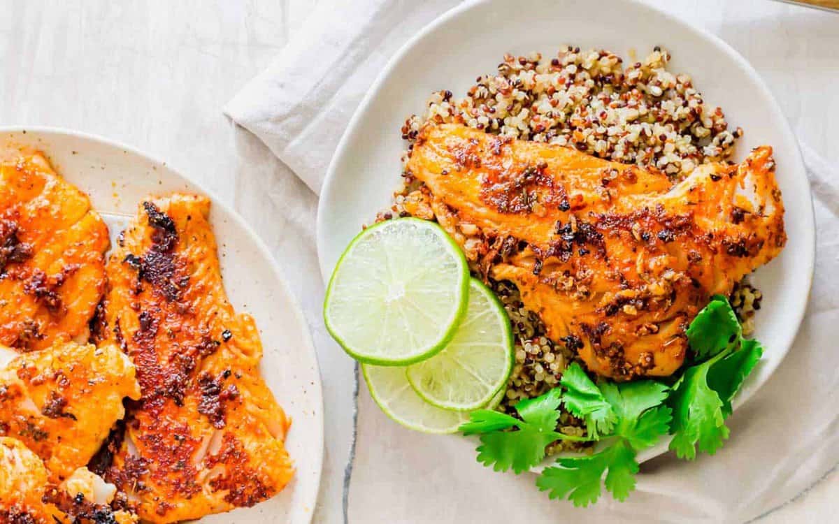 A plate of food with limes, a bowl of quinoa, and fresh flavors—perfect for those seeking easy seafood dinner ideas.
