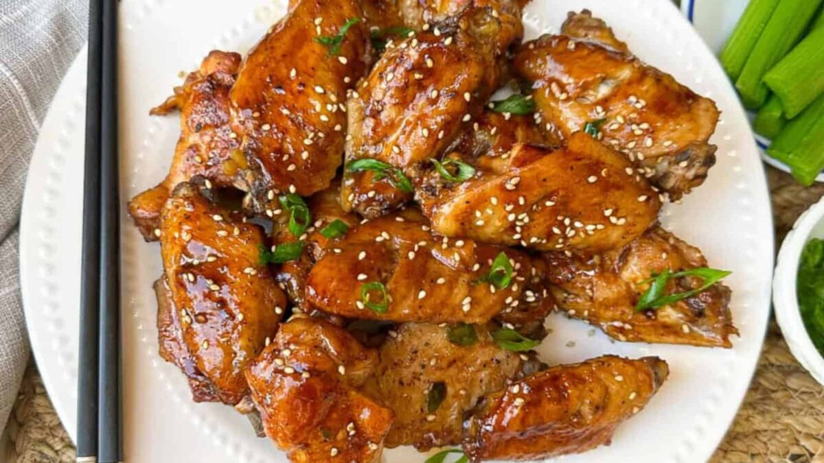 A plate of glazed chicken wings garnished with sesame seeds and chopped green onions, served on a white dish—perfect for those seeking delicious gluten-free recipes.