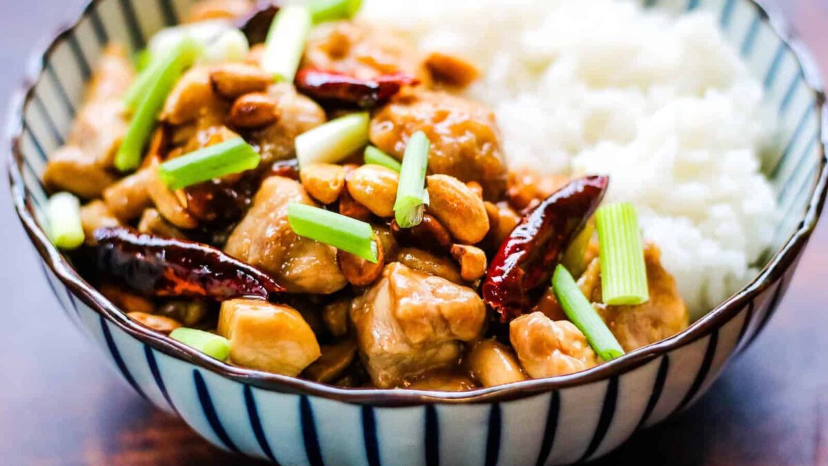 A bowl of Kung Pao chicken with diced chicken, peanuts, dried red chilies, green onions, and white rice—perfect for 30 Minute Dinners that deliver main character energy to your table.