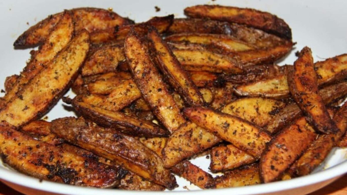 A white dish filled with seasoned, baked potato wedges, showing a crispy texture and golden-brown color—perfect for those who love creative fries.