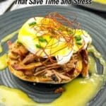 An English muffin topped with pulled meat, a poached egg, and garnished with sliced green onions and thin chili threads, with hollandaise sauce on a dark plate.