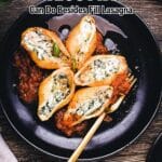Large pasta shells stuffed with ricotta cheese and spinach are served on a bed of tomato sauce on a black plate with a fork.