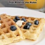 Two waffles topped with blueberries and butter sit on a white plate, with a glass of orange juice visible in the background. Text reads “11 Waffle Recipes That Rewrite the Rules.”.