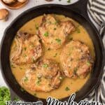 A cast iron skillet with four pork chops in a creamy mushroom sauce, garnished with parsley, surrounded by fresh mushrooms and herbs.