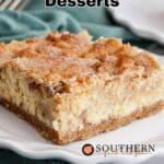 A close-up of a slice of snickerdoodle dessert bar on a white plate, with a fork and green cloth in the background. Text reads "12 Snickerdoodle Desserts.