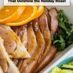 Sliced ham garnished with orange slices and parsley, served in a dish with lettuce on the side; text overlay reads โ14 Ham Recipes That Outshine the Holiday Roast.โ.