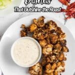 A plate of roasted cauliflower with a bowl of dipping sauce, surrounded by celery sticks and dried red chili peppers. Text reads, "14 Roasted Side Dishes That Outshine the Roast.