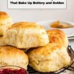 A stack of golden, fluffy biscuits on a cooling rack, with a bowl of red jam and the text "15 Biscuit Recipes That Bake Up Buttery and Golden" above.