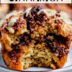 Close-up of a cinnamon muffin with a bite taken out, topped with icing; text reads "15 cozy bakes and breakfasts with cinnamon.