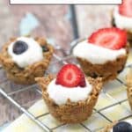 Mini granola cups filled with yogurt and topped with fresh strawberries and blueberries, displayed on a cooling rack.