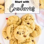 A plate of cranberry cookies sits on a white surface with more cookies and a striped towel nearby. Text reads: "16 Sweet Treats That Start with Cranberries.