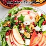 A bowl of salad with apple slices, walnuts, feta cheese, arugula, and pomegranate seeds, with small bowls of pomegranate seeds and walnuts in the background. Text reads "17 Salad Recipes That Make Eating Fun.