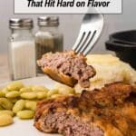 A fork holds a piece of cooked steak over a plate with more steak, lima beans, mashed potatoes, and a roll; salt and pepper shakers are in the background.