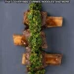 Three cooked beef ribs topped with green herb sauce are arranged on a gray plate. Text above reads: "9 Instant Pot Meals That Cover Ribs, Curries, Noodles, and More.