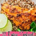 A plate with a cooked fish fillet on a bed of quinoa, garnished with lime slices and greens. Text overlay reads "22 Easy Seafood Dinners.