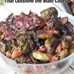 A glass bowl filled with roasted Brussels sprouts and bacon sits on a white surface. Text above reads “22 Side Dishes That Outshine the Main Course.”.