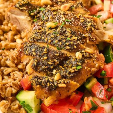 Sliced seasoned chicken breast with a side of cooked grain and mixed fresh vegetables, served on a white plate with a fork—perfect for those looking for delicious dairy-free recipes.