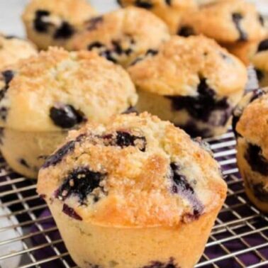 Freshly baked blueberry muffins with crumb topping are arranged on a wire cooling rack—discover unique muffins and creative muffin recipes perfect for any occasion.